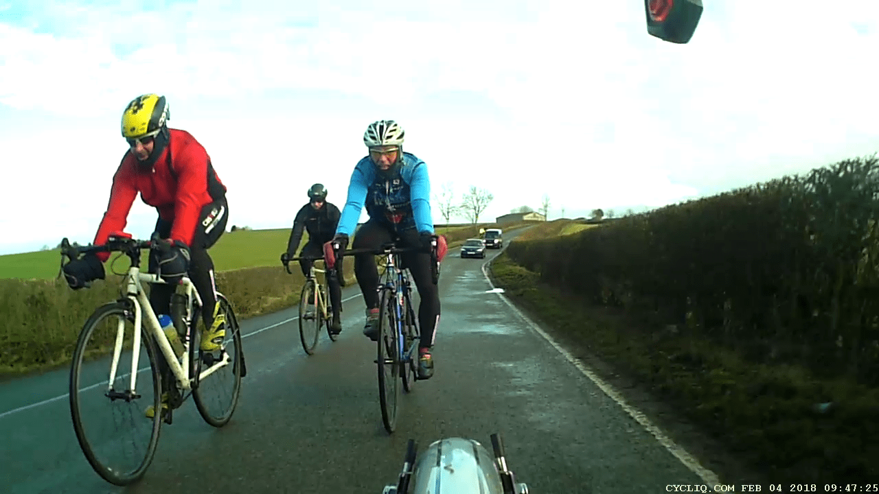 A group of cylicts riding on a road wrapped up in warm clothes.